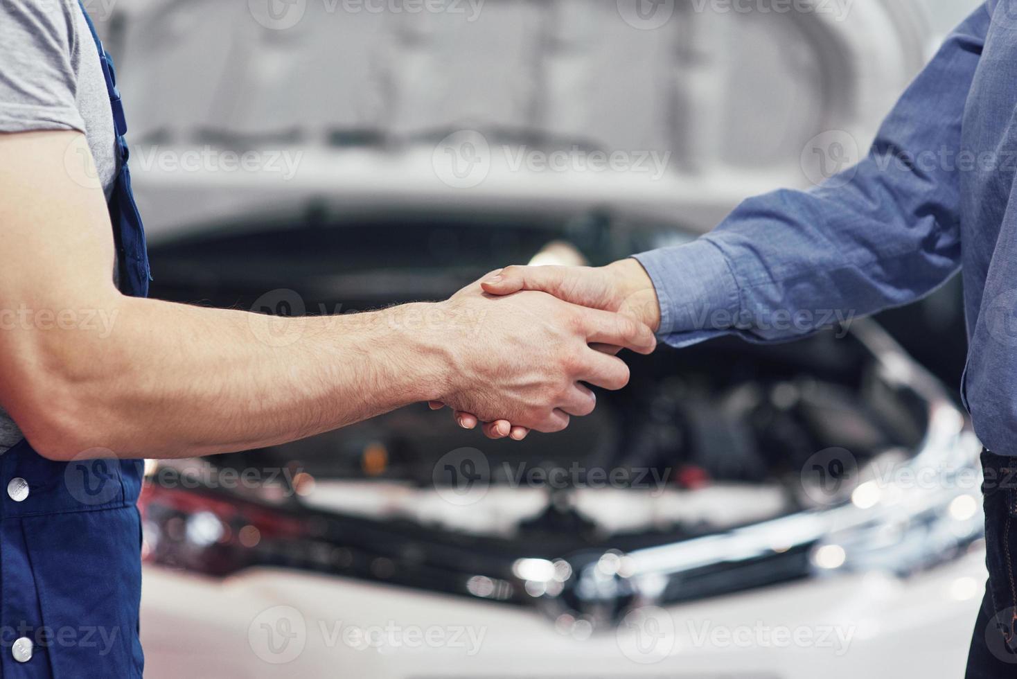 man automonteur en vrouw klant maken een overeenkomst over de reparatie van de auto foto