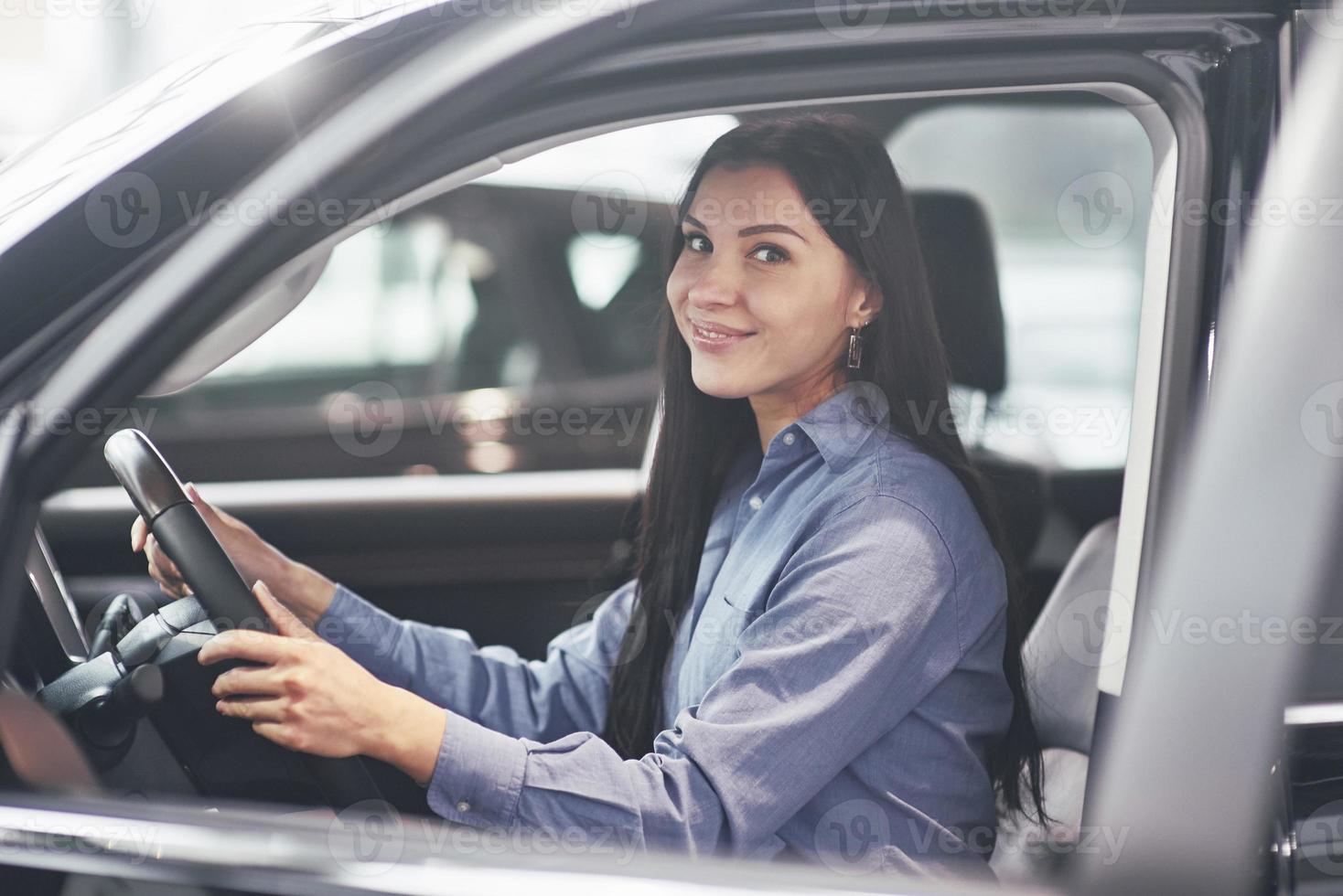 autozaken, autoverkoop, consumentisme en mensenconcept - gelukkige vrouw die autosleutel van dealer in autoshow of salon neemt foto