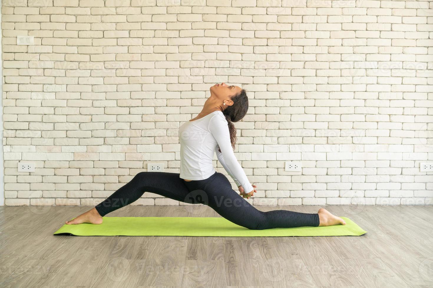 latijnse vrouw die yoga beoefent op mat foto