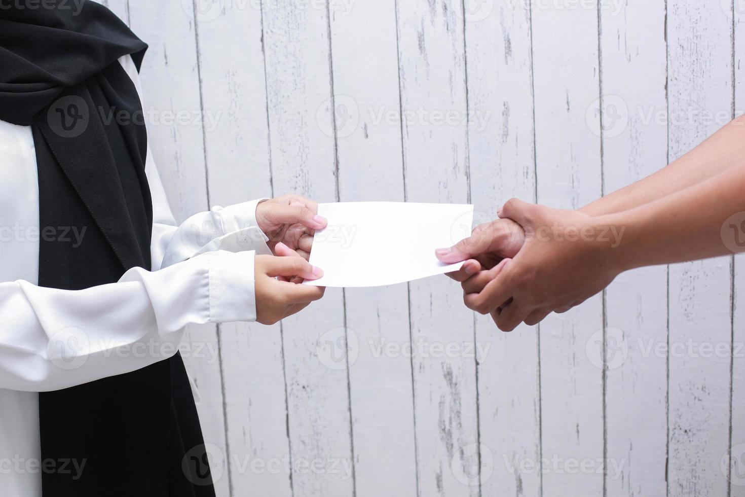 hand met witte envelop om zakat fitrah te geven of te betalen als een verplichting in de heilige maand ramadan foto