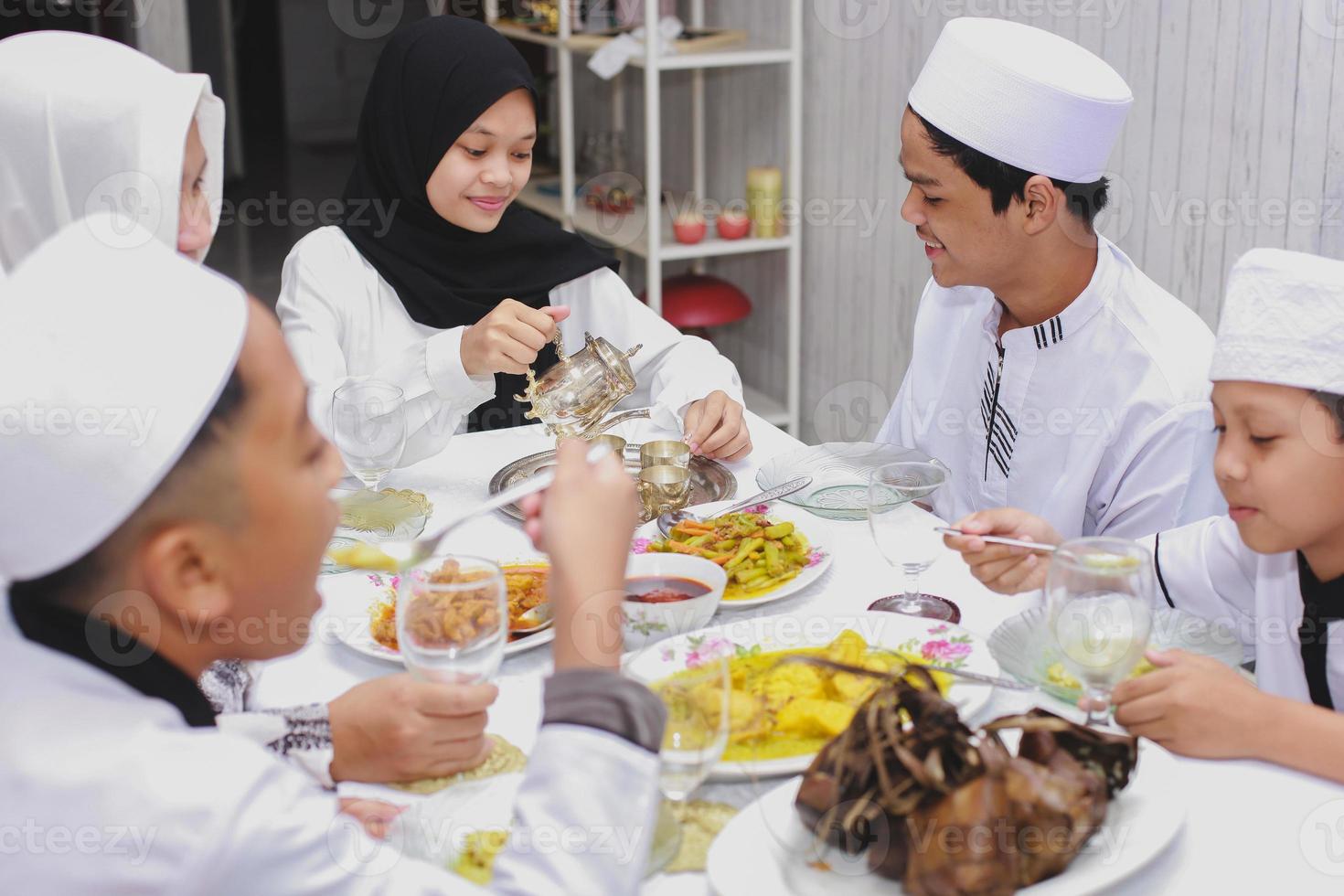 gelukkige familie komt samen en eet samen in de eetkamer tijdens de viering van eid Mubarak foto