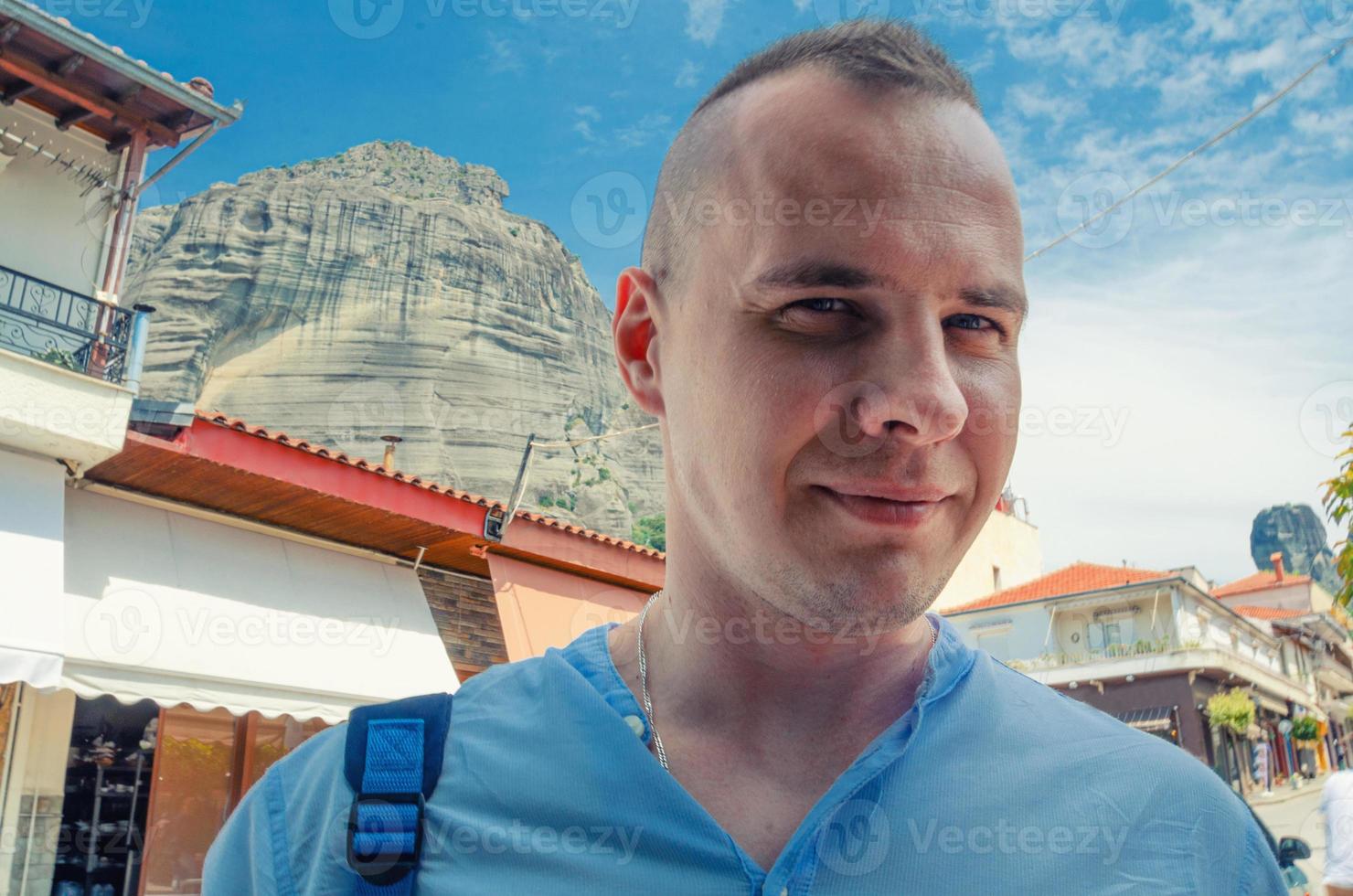 close-up portret van een jonge man die naar de camera kijkt, poseert en glimlacht buiten in de stad Kalabaka foto