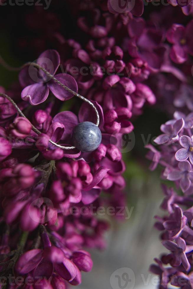 ketting gemaakt van natuursteen met zilveren beslag met paars violet lila bloemen op witte struisvogelveren. zilveren accessoires. foto