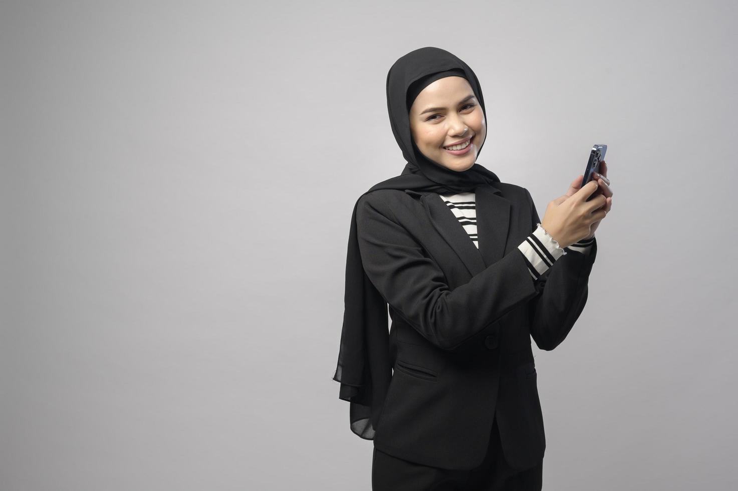 portret van mooie vrouw met hijab met behulp van mobiele telefoon op witte achtergrond foto