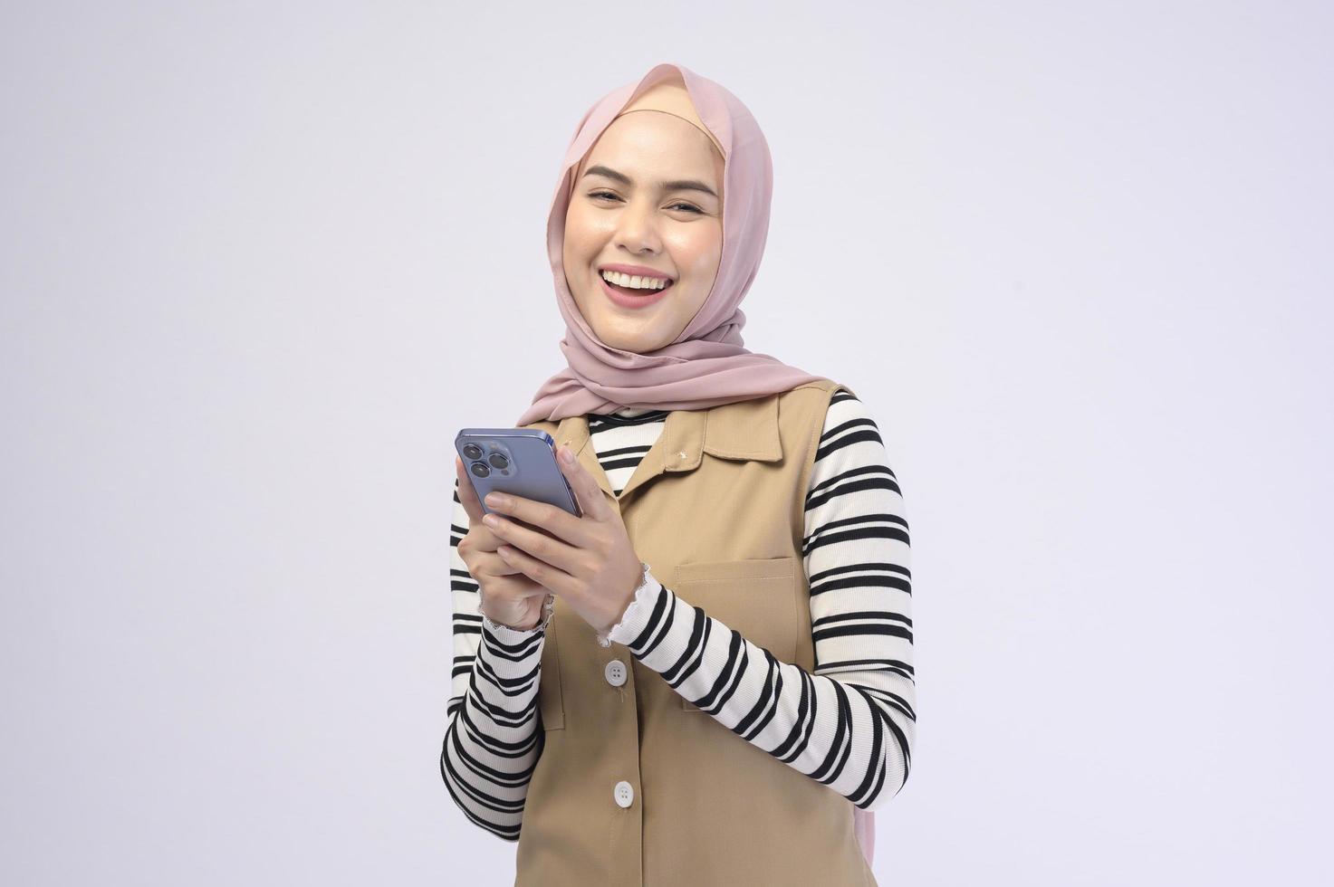 portret van mooie vrouw met hijab met behulp van mobiele telefoon op witte achtergrond foto