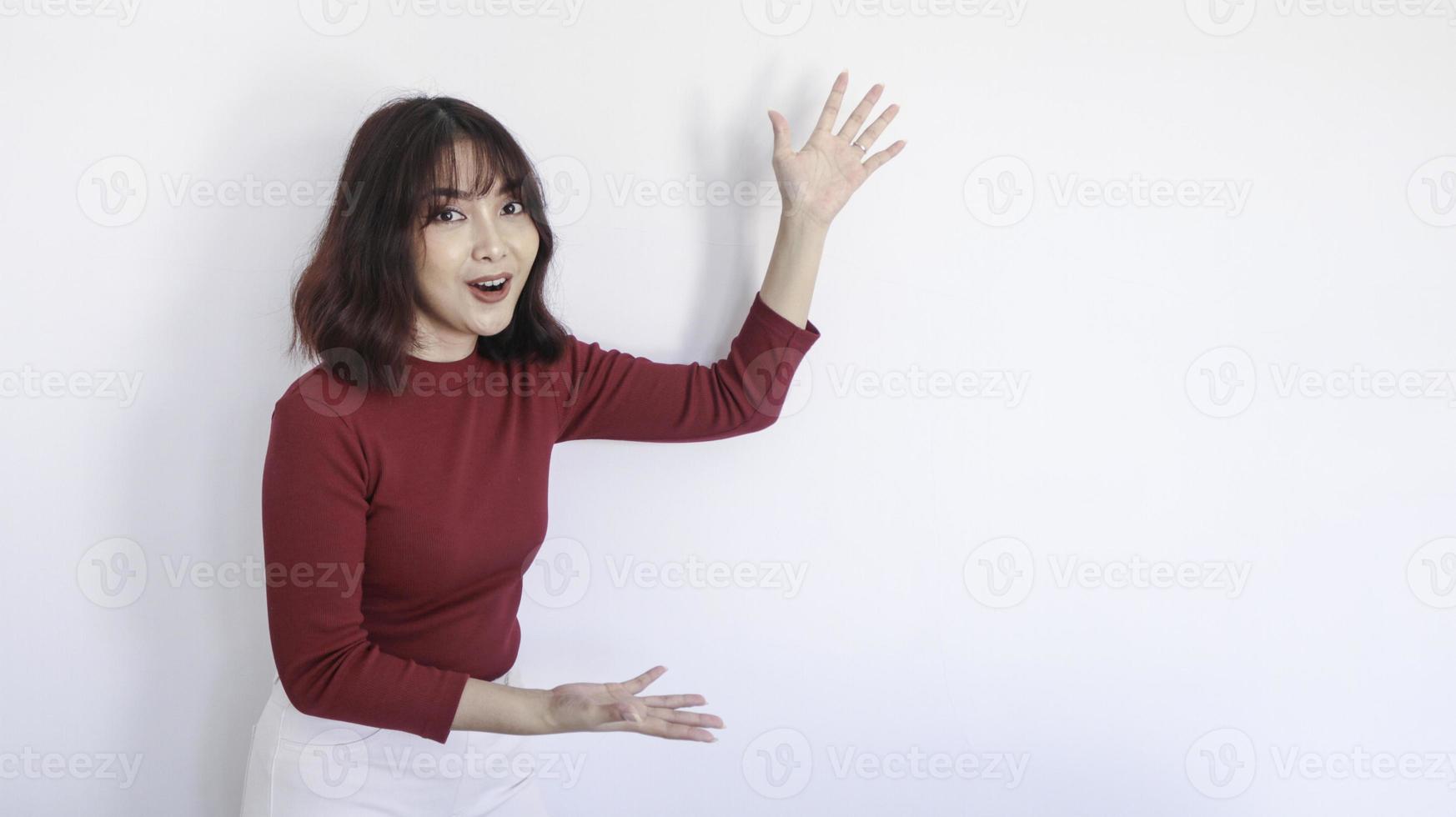 schok aziatisch mooi meisje wijst naast haar met rood shirt op witte achtergrond foto