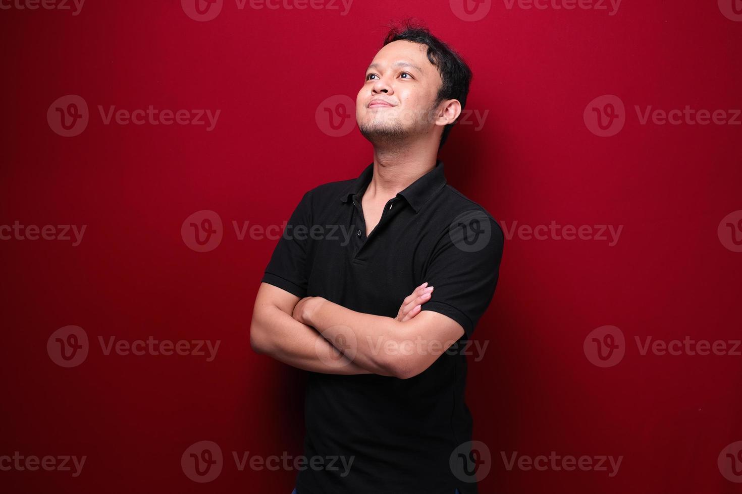 portret van lachende jonge Aziatische man met zwart shirt geïsoleerd op rood. foto