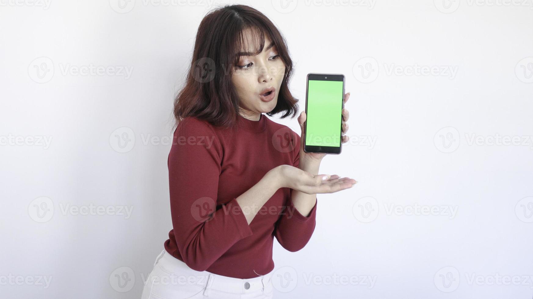 schok Aziatische mooi meisje punt op groen scherm telefoon op witte achtergrond foto