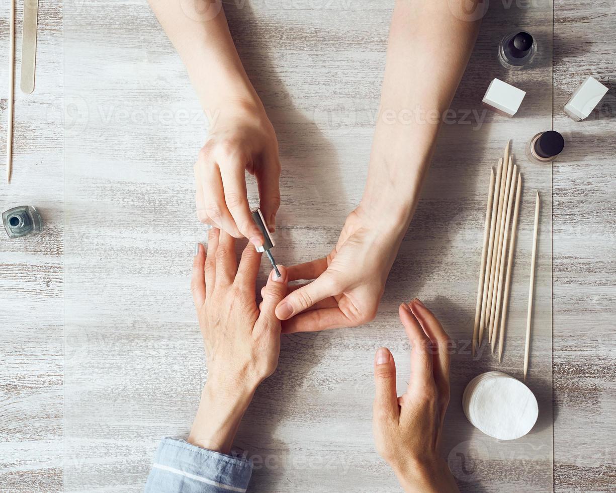 moeder en dochter doen manicure, lakken nagels met vernis. thuiszorg tijdens quarantaine foto