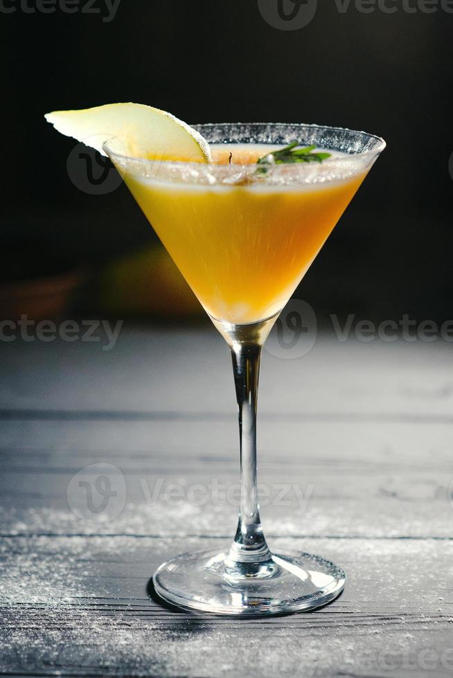 gele alcohol peer cocktail peer op donkere achtergrond foto