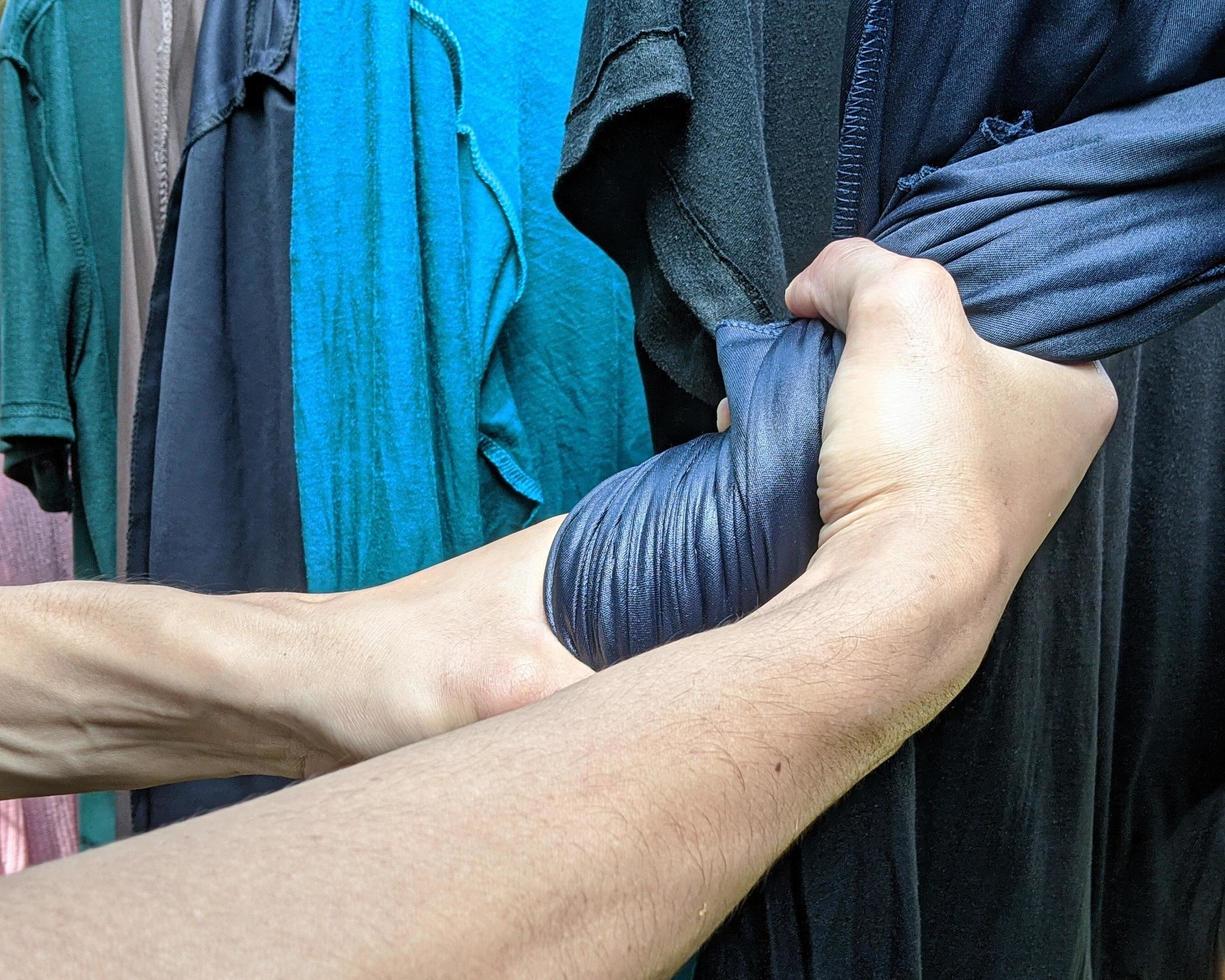 beide handen wringen kleren om snel te drogen. illustratie van het wassen en drogen van kleding voor huishoudelijke activiteiten. foto