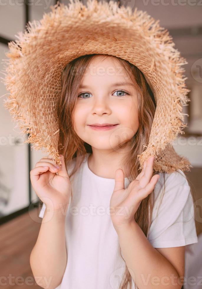 schattig vrolijk meisje in strohoed thuis binnen. mode, stijl, jeugd, emoties, opgroeien concept foto