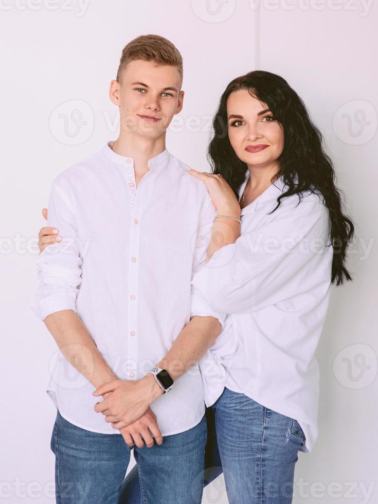 brunette mooie stijlvolle vrouw met tiener zoon in witte shirts en jeans. familie, stijl, relatief concept foto