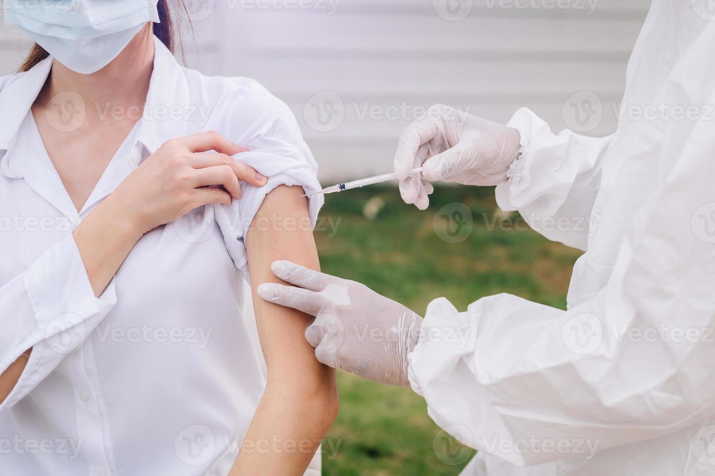 arts die de spuit vasthoudt voordat hij de patiënt injecteert met een medisch masker. covid-19 of coronavirusvaccin foto