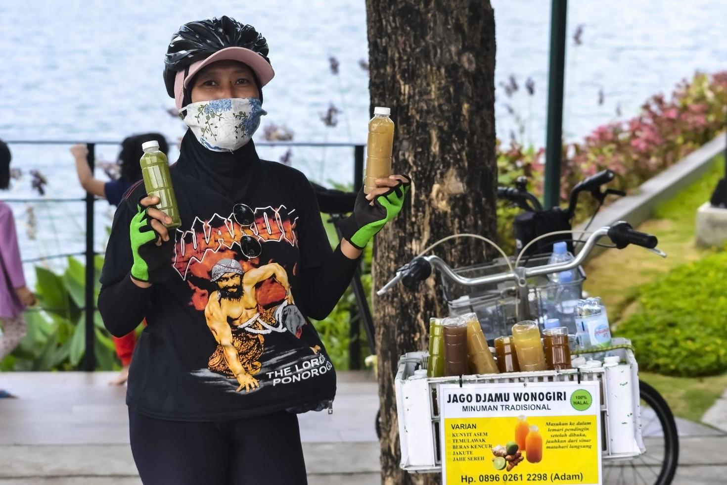 bekasi, west java, indonesië, 5 maart 2022. een vrouw die kruidengeneesmiddelen verkoopt, verkoopt haar kruidengeneesmiddel op een fiets foto