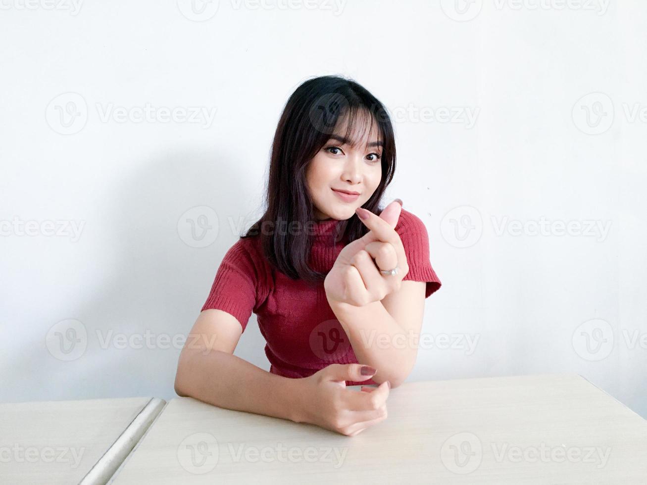 Aziatische mooi lachende meisje liefde korea teken met vinger met onscherpe achtergrond geïsoleerde witte achtergrond tonen. Indonesische vrouwen foto