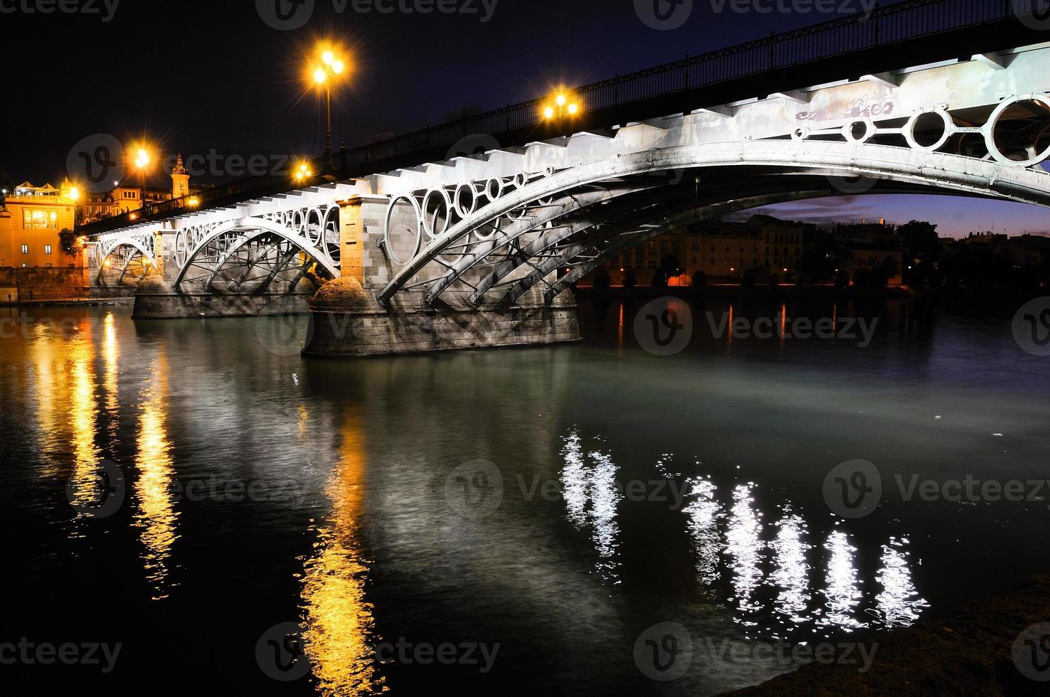 triana-brug over de rivier guadalquivir bij zonsondergang met rivierreflecties foto