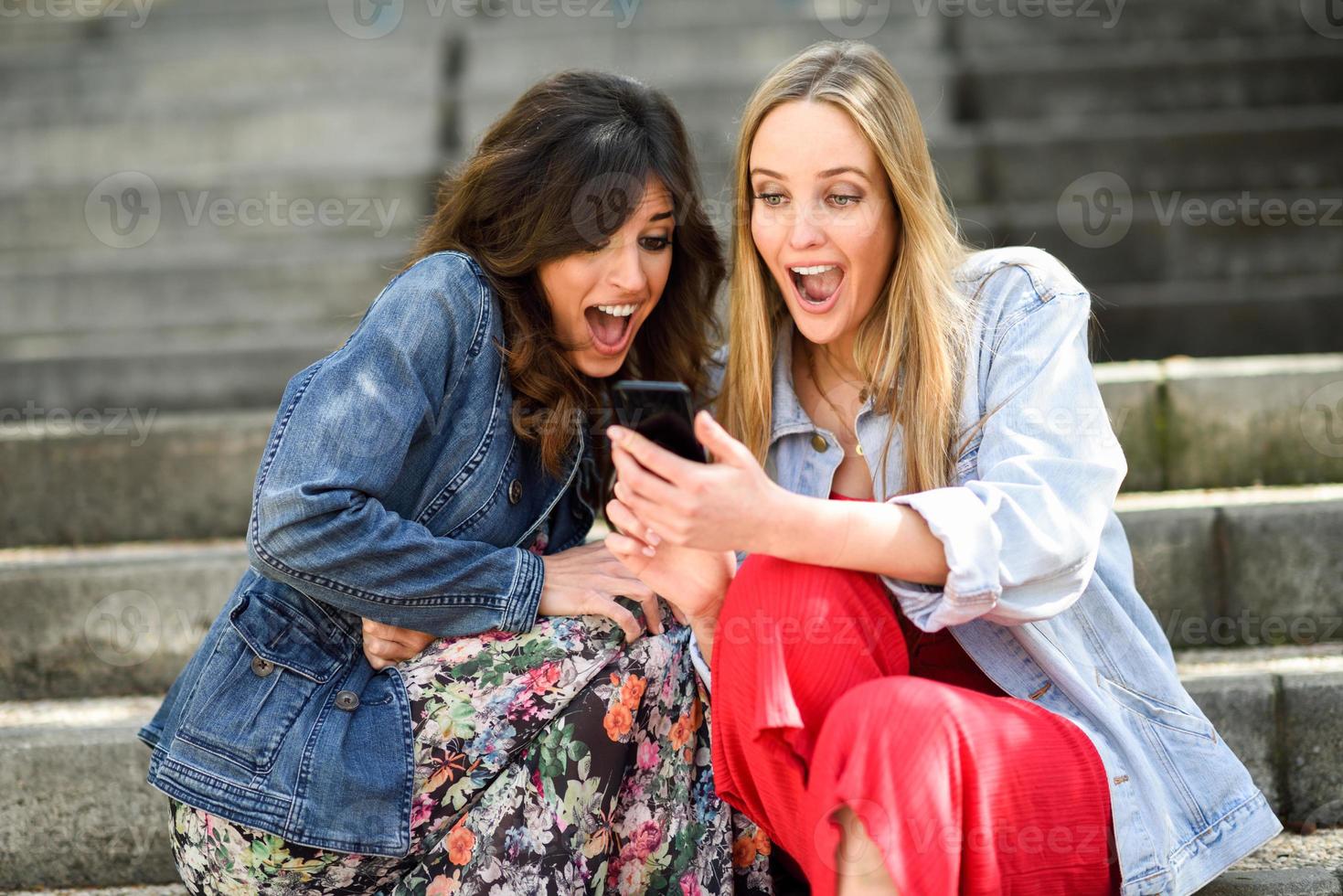 twee jonge vrouwen die er geweldig uitzien op hun smartphone foto