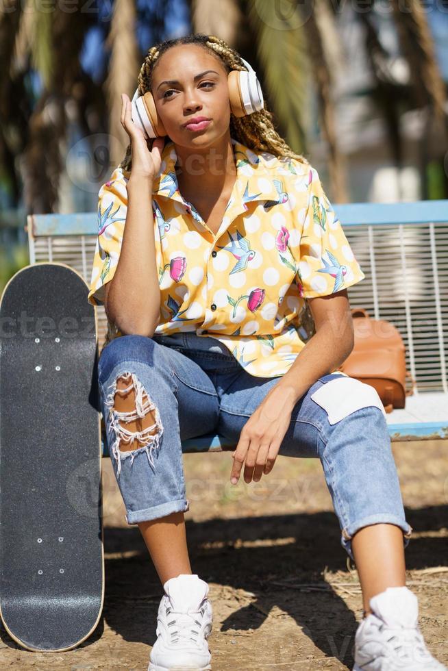 Afro-Amerikaanse vrouwelijke skater die naar muziek luistert foto