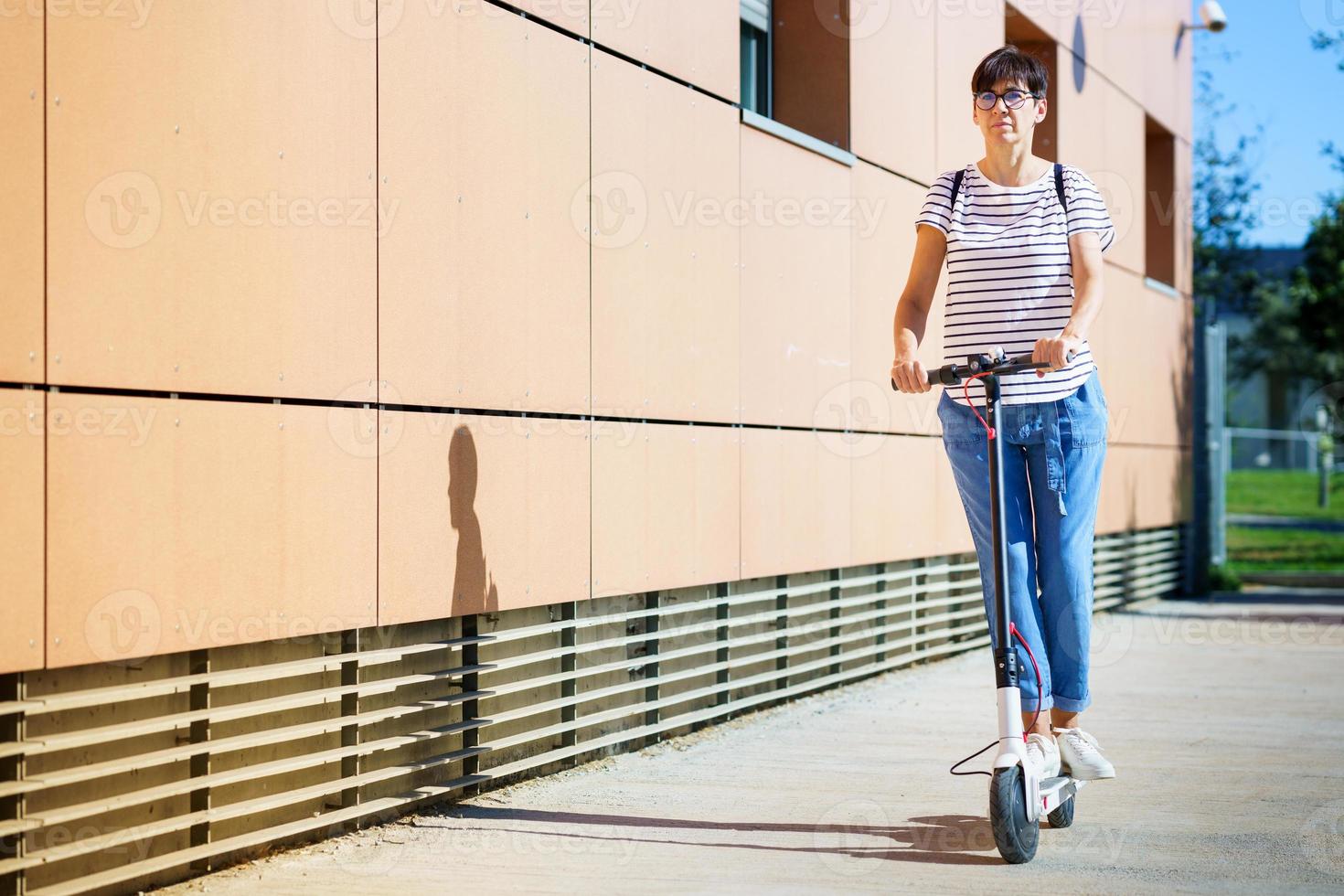 vrouw rijdt door de stad op een elektrische scooter foto