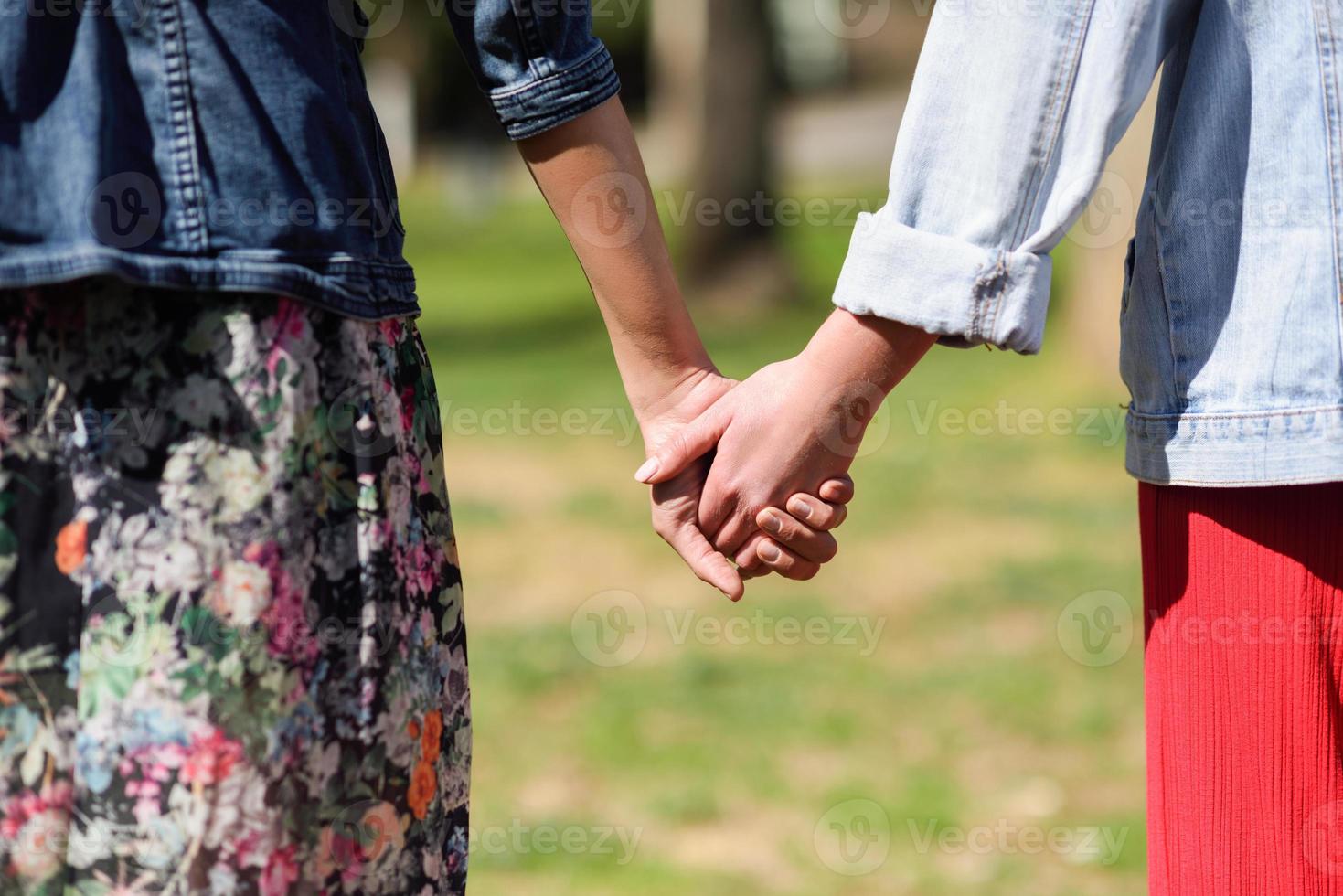 twee jonge vrouwen wandelen met haar handen in stadspark. foto