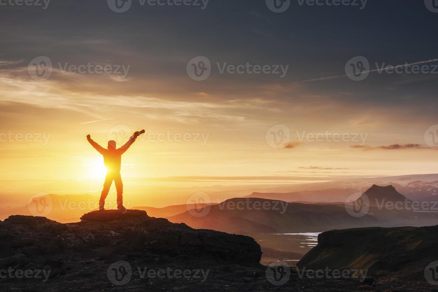 gelukkige man die bij zonsondergang op een klif staat foto