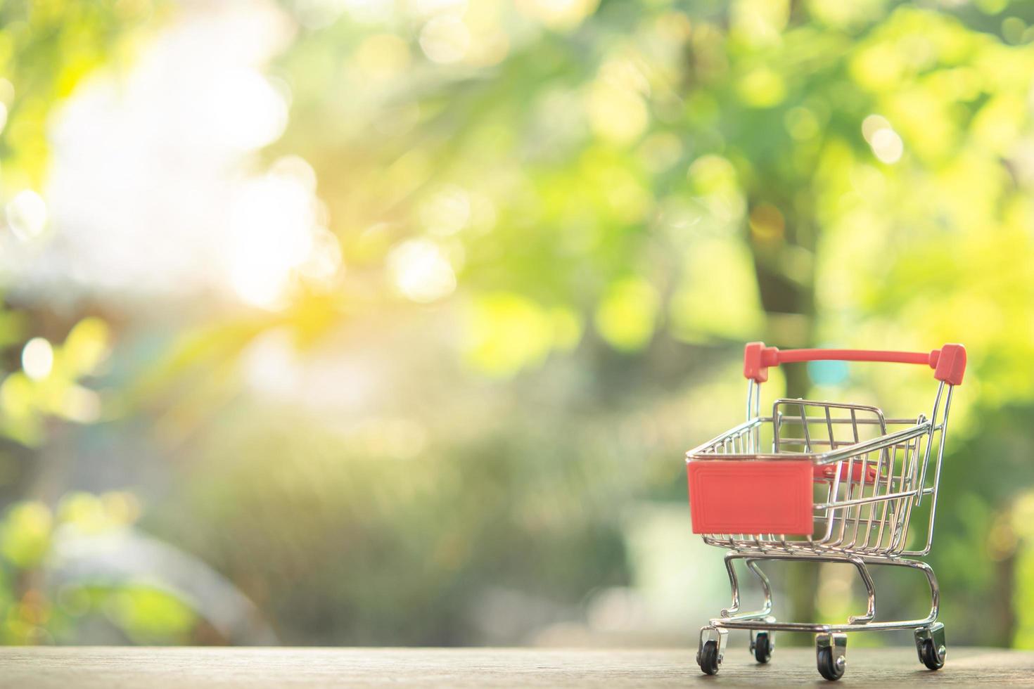 shopping concept - lege winkelwagen of trolley op bruin houten tafel. online winkelen consumenten kunnen winkelen vanuit huis en bezorgservice. met kopie ruimte foto