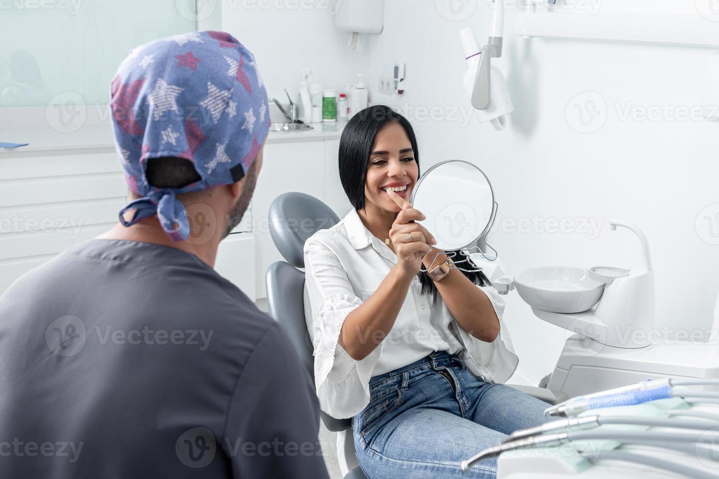 cient glimlachen en kijken naar een spiegel in een tandheelkundige kliniek foto
