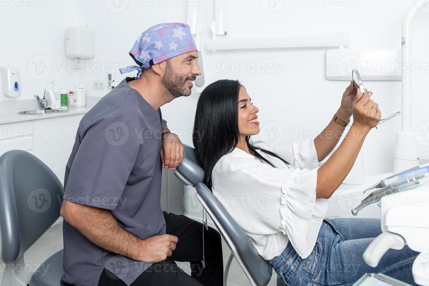 cliënt kijkt naar zijn tanden in de spiegel naast een tandarts in een kliniek foto