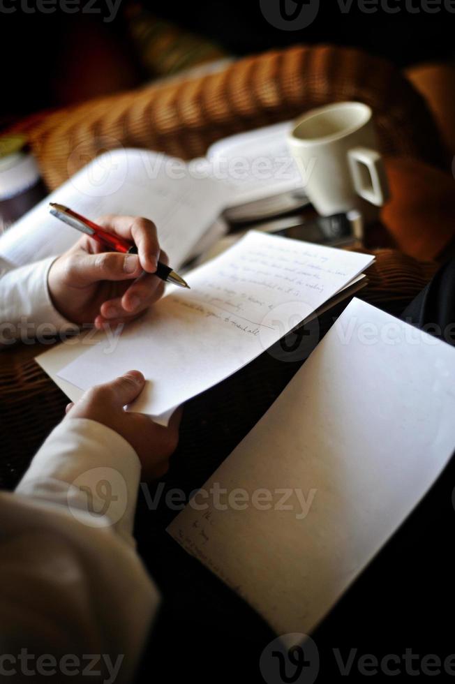 close-up beeld van een man die met een pen op een stuk papier schrijft foto