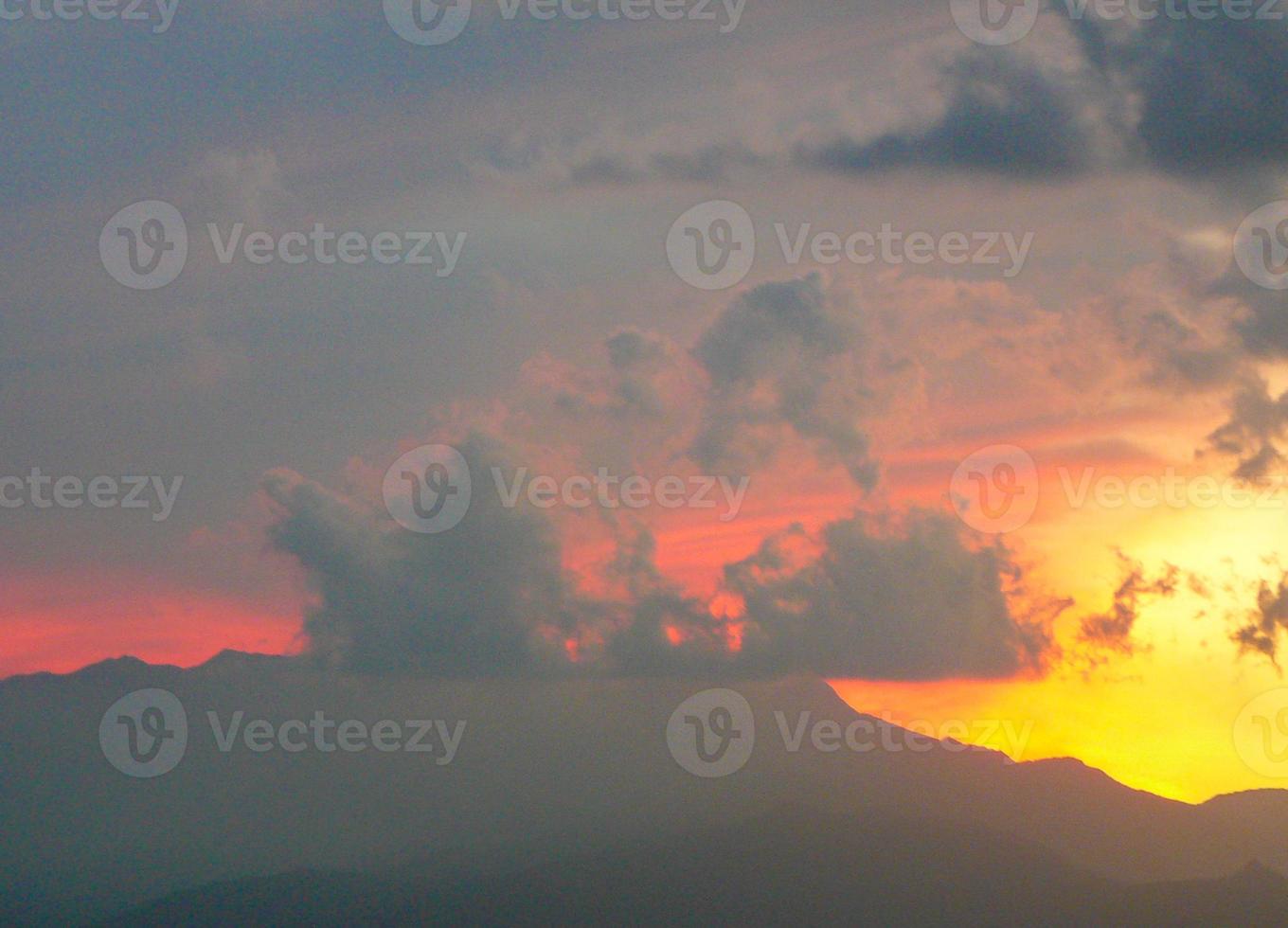 rode zonsondergang met wolken en bergen skyline foto