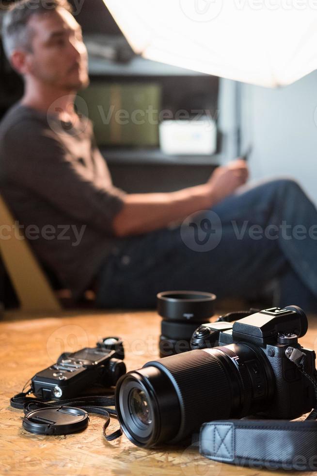 camera en apparatuur op tafel in de studio op de achtergrond van de zittende fotograaf foto