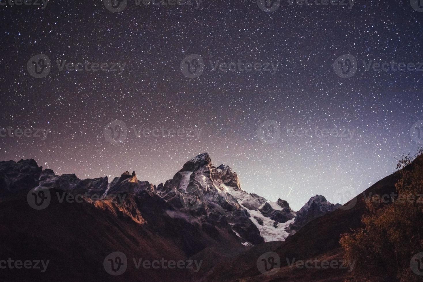 fantastische sterrenhemel. herfstlandschap en besneeuwde toppen foto