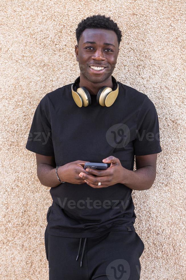 inhoud Afro-Amerikaanse man die lacht terwijl hij berichten op smartphone op straat foto