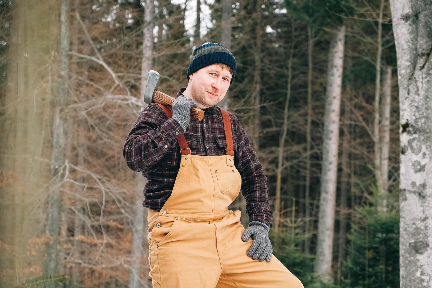 portret van een man houthakker met een bijl in zijn handen op een achtergrond van bos en bomen foto