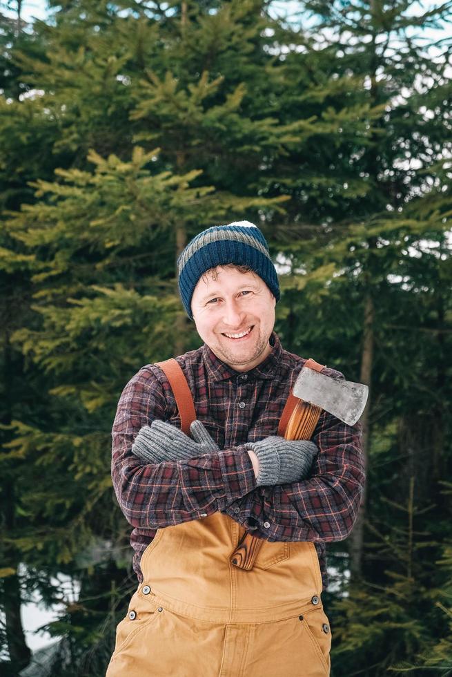 portret van een man houthakker met een bijl in zijn handen op een achtergrond van bos en bomen foto