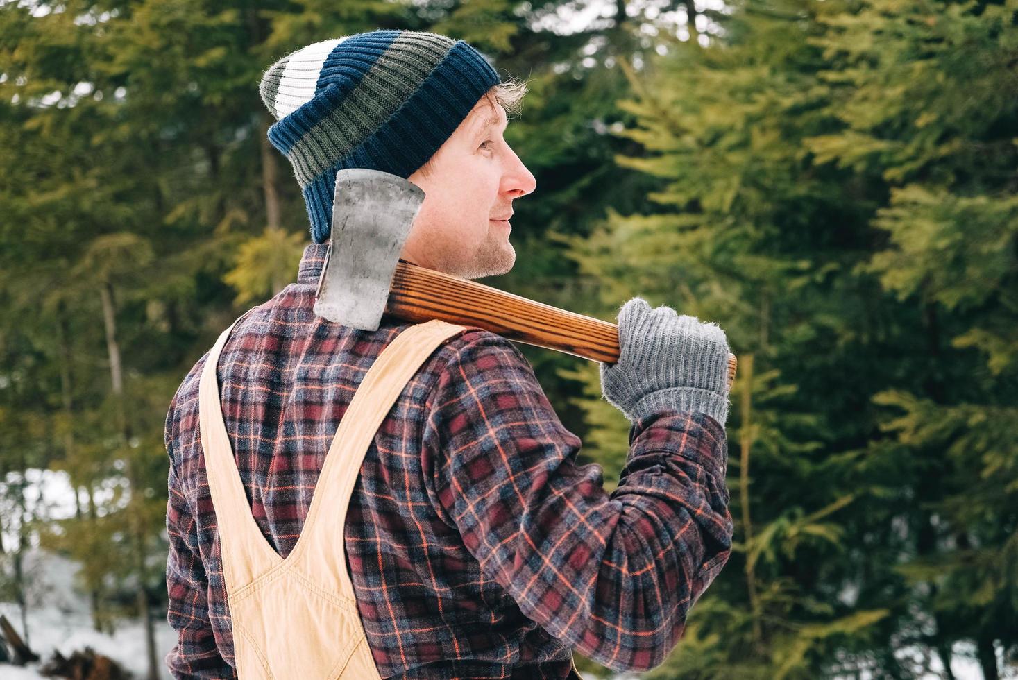 portret van een man houthakker met een bijl in zijn handen op een achtergrond van bos en bomen foto