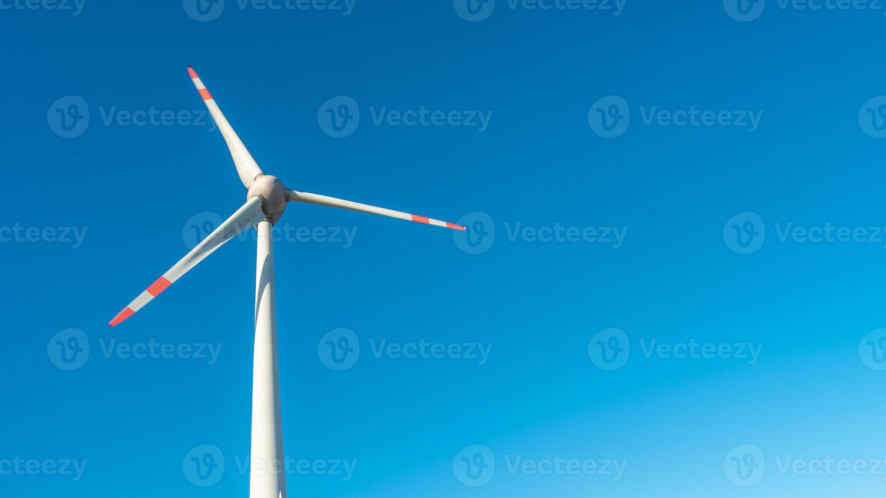 banner met een eenzame grote windturbine om elektrische energie op te wekken als groene milieuvriendelijke energie bij blauwe turquoise deep sky en kopieer de ruimteachtergrond. concept van duurzame schone industrie en leven. foto