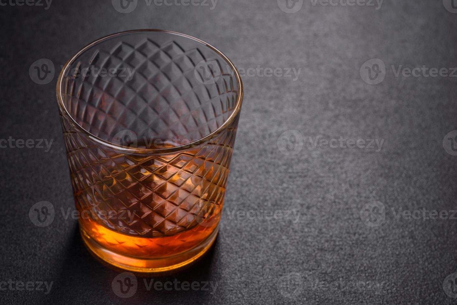 een glas whisky of cognac op een zwarte betonnen tafel. ontspanningstijd foto