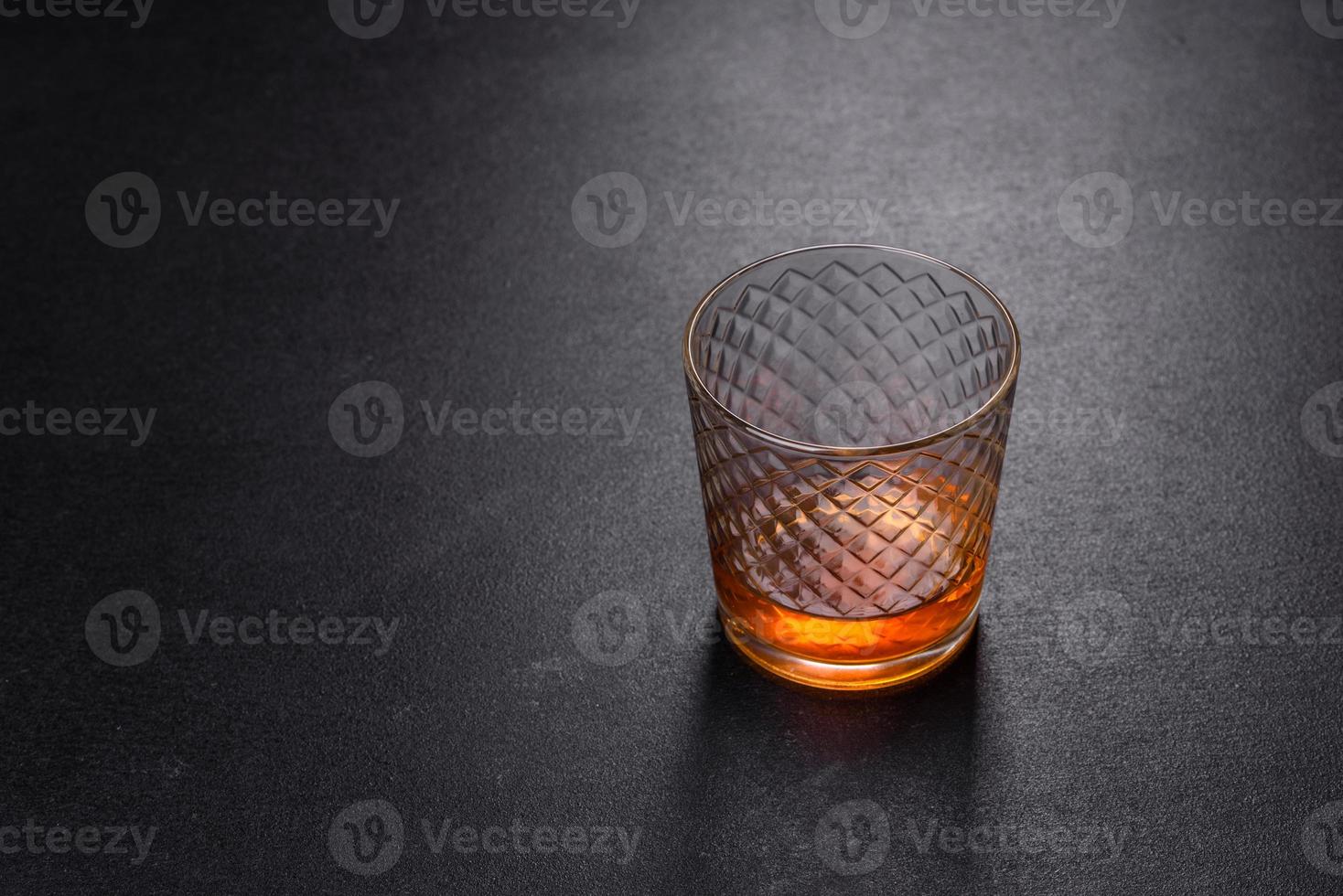 een glas whisky of cognac op een zwarte betonnen tafel. ontspanningstijd foto