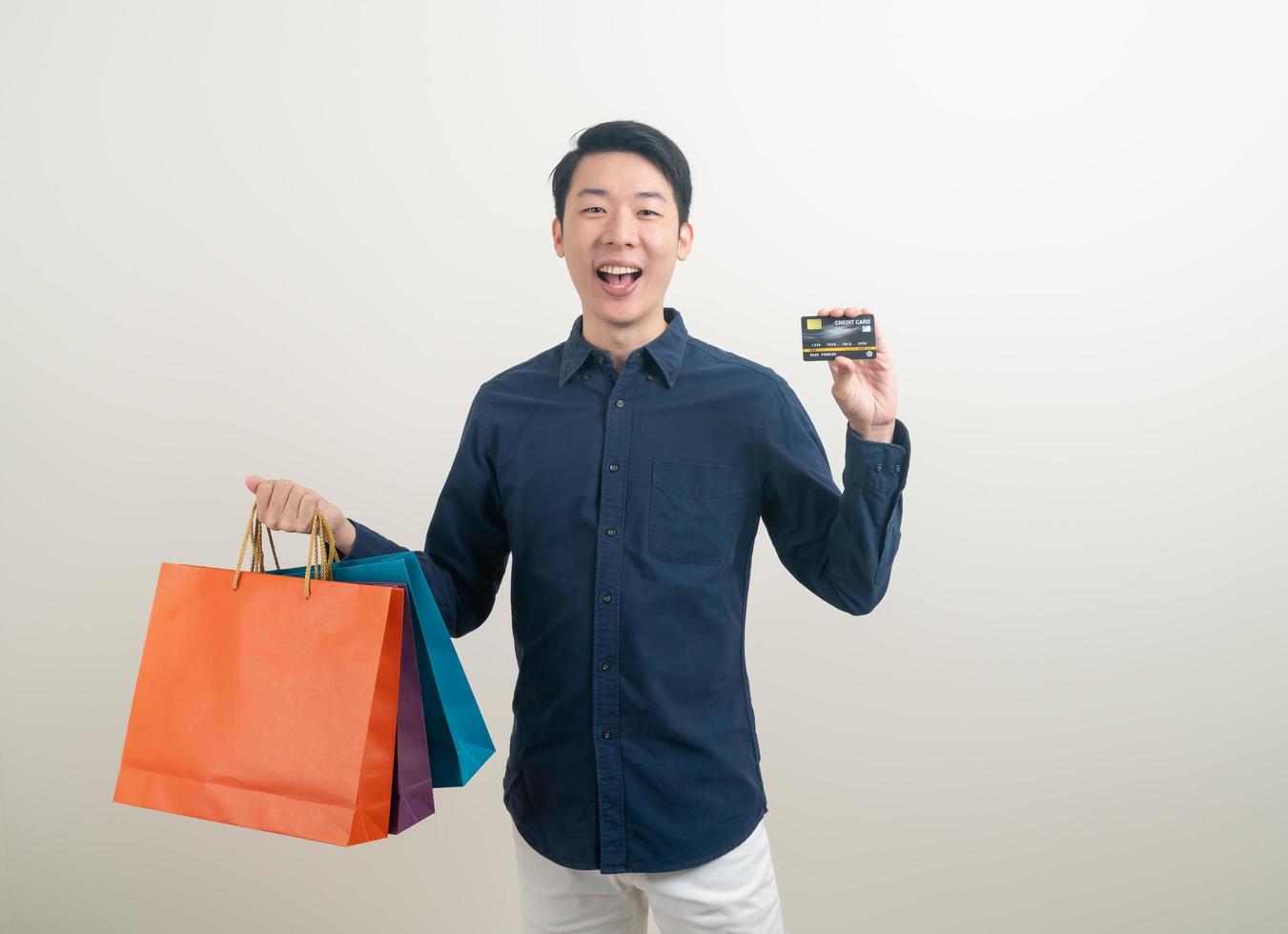 portret jonge aziatische man met creditcard en boodschappentas foto