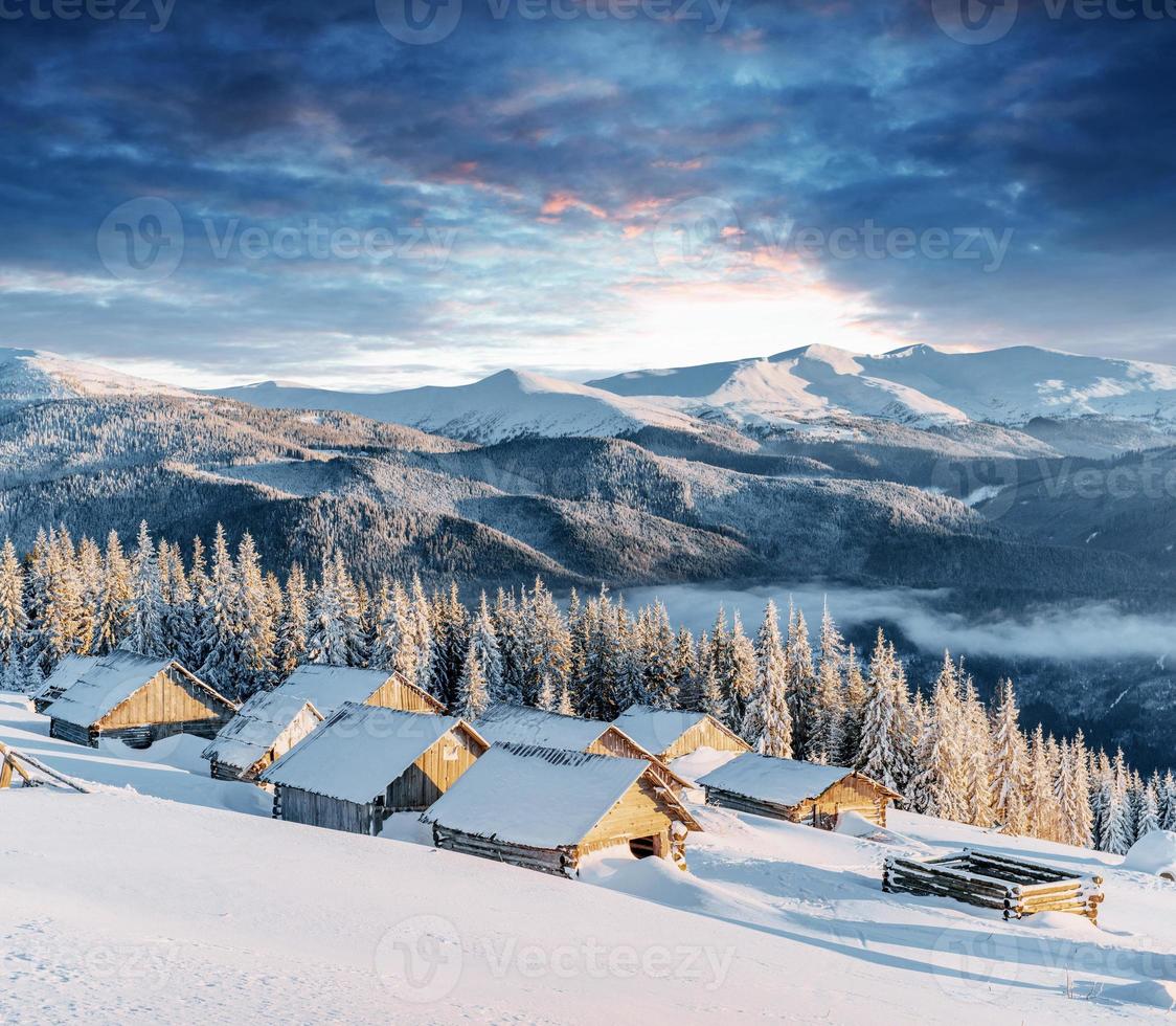 fantastische zonsondergang over met sneeuw bedekte bergen en houten chalets foto