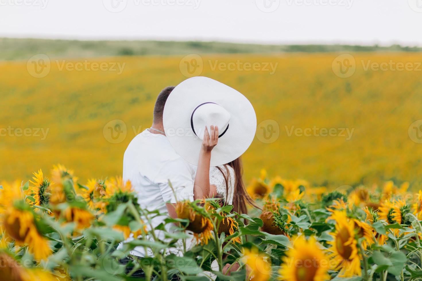 verliefde paar zoenen in een veld met zonnebloemen. familie tijd samen doorbrengen op de natuur. selectieve focus foto