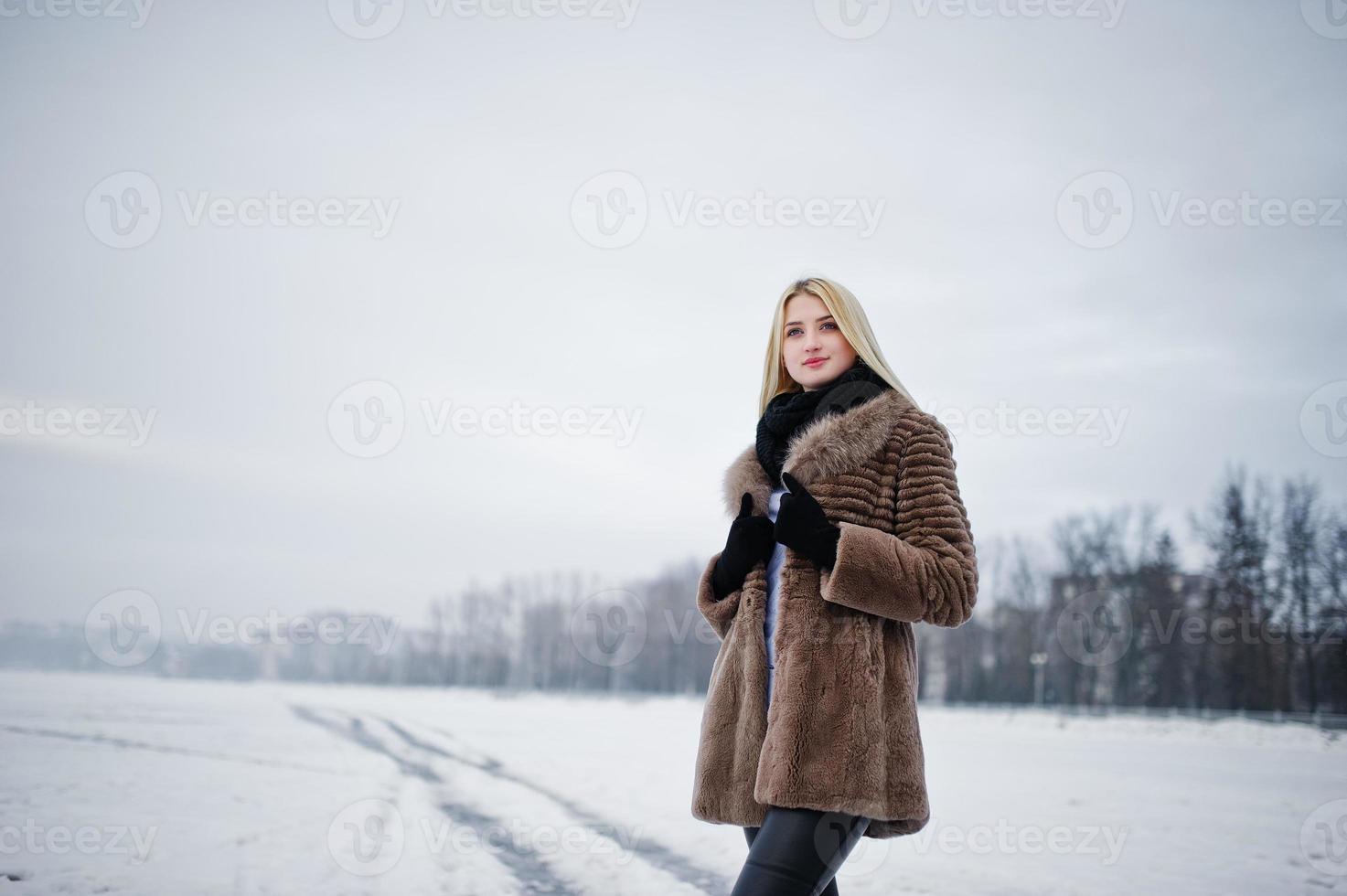 portret van jonge elegantie blond meisje in een bontjas achtergrond mistige rivier op winterijs. foto