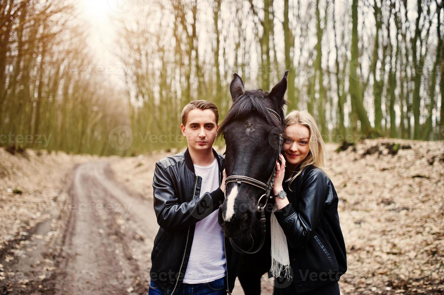 jonge stijlvolle paar verliefd in de buurt van paard in herfst bos. foto