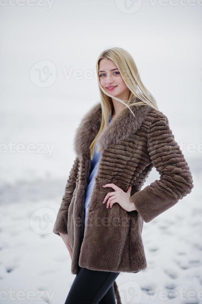 portret van jonge elegantie blond meisje in een bontjas achtergrond mistige rivier op winterijs. foto