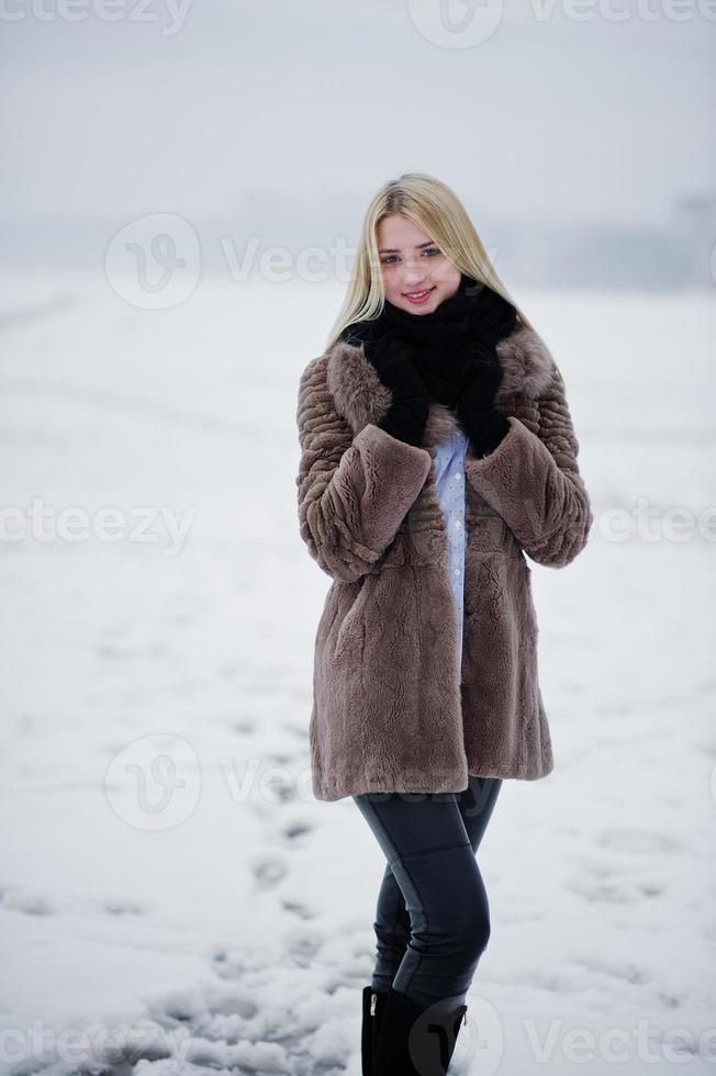 portret van jonge elegantie blond meisje in een bontjas achtergrond mistige rivier op winterijs. foto