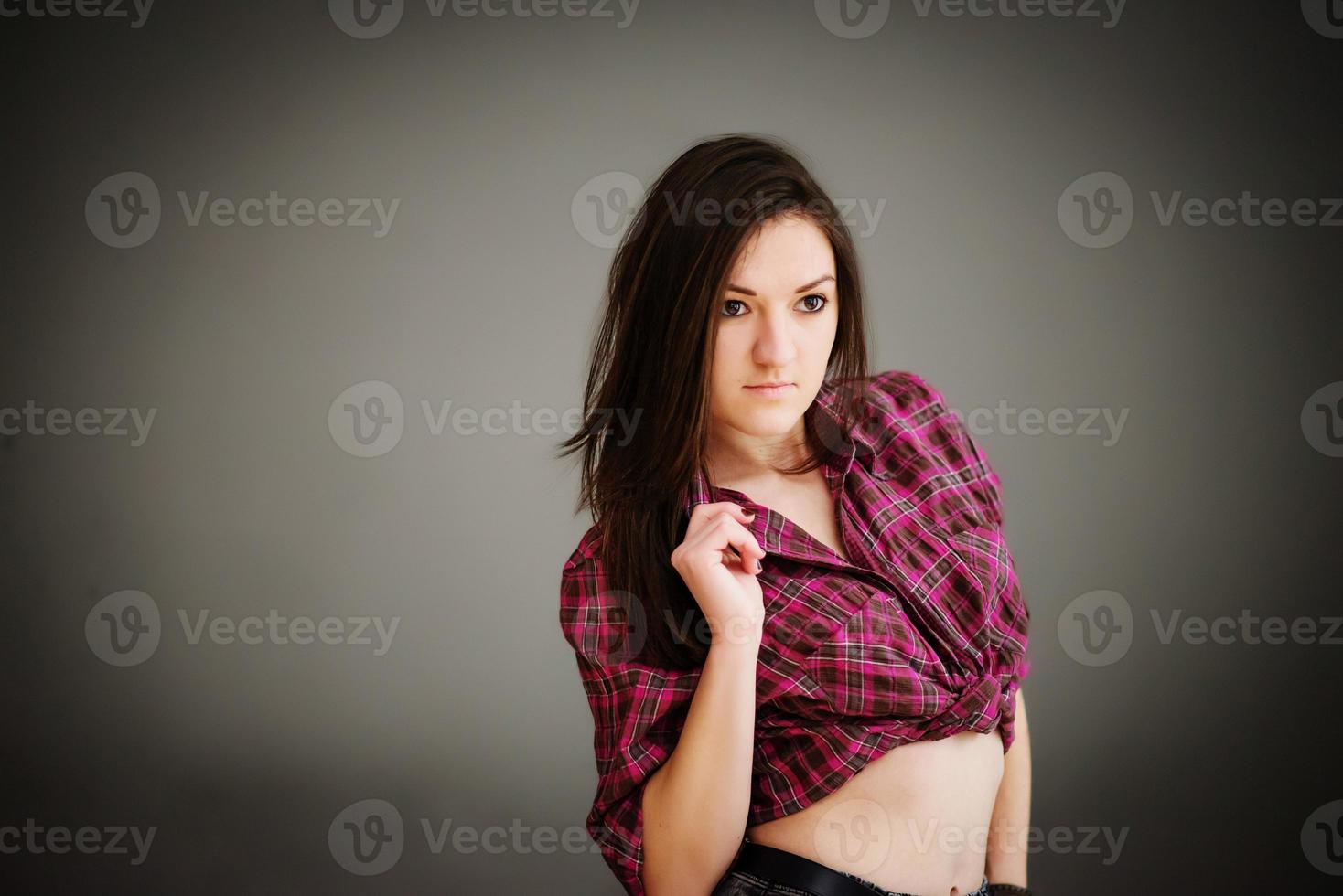 portret van donkerbruin meisje die vrijetijdskleding grijze muur als achtergrond dragen. foto