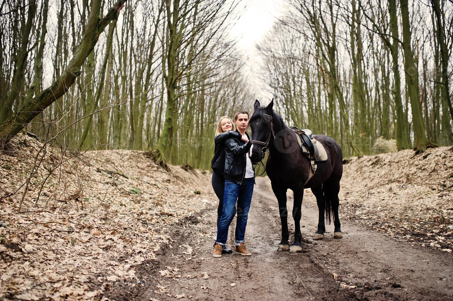 jonge stijlvolle paar verliefd in de buurt van paard in herfst bos. foto