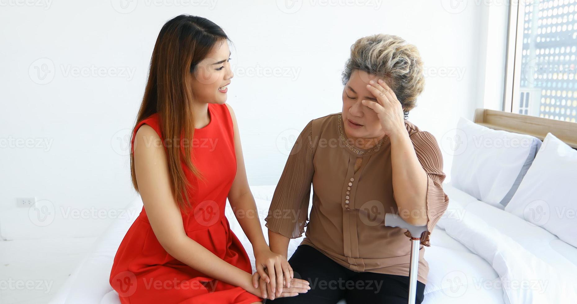 vrolijke aziatische vrouw die thuis voor haar grootmoeder in de slaapkamer zorgt foto